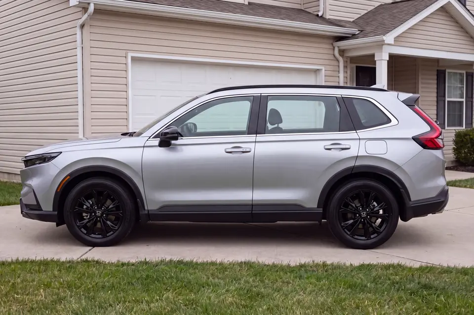 Side view of a silver compact SUV parked in a driveway, photographed from the driver's side.